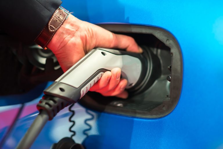 EV Car or Electric car at charging station with the power cable supply plugged in on blurred Night